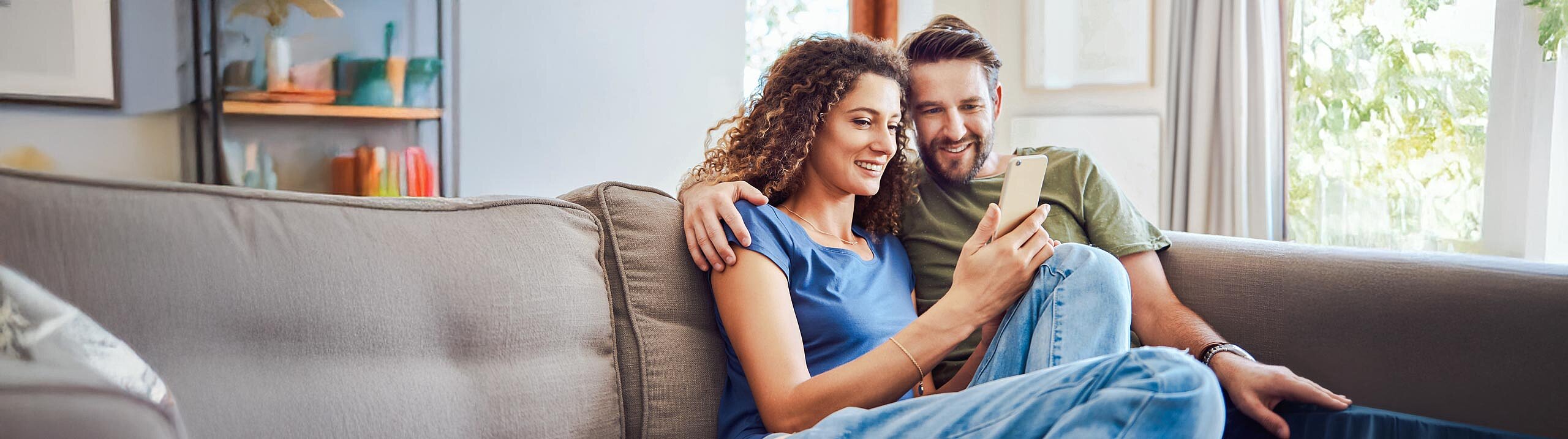 Mann sitzt mit Frau auf der Couch am Handy