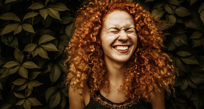 Frau mit lockigen, roten Haaren lacht