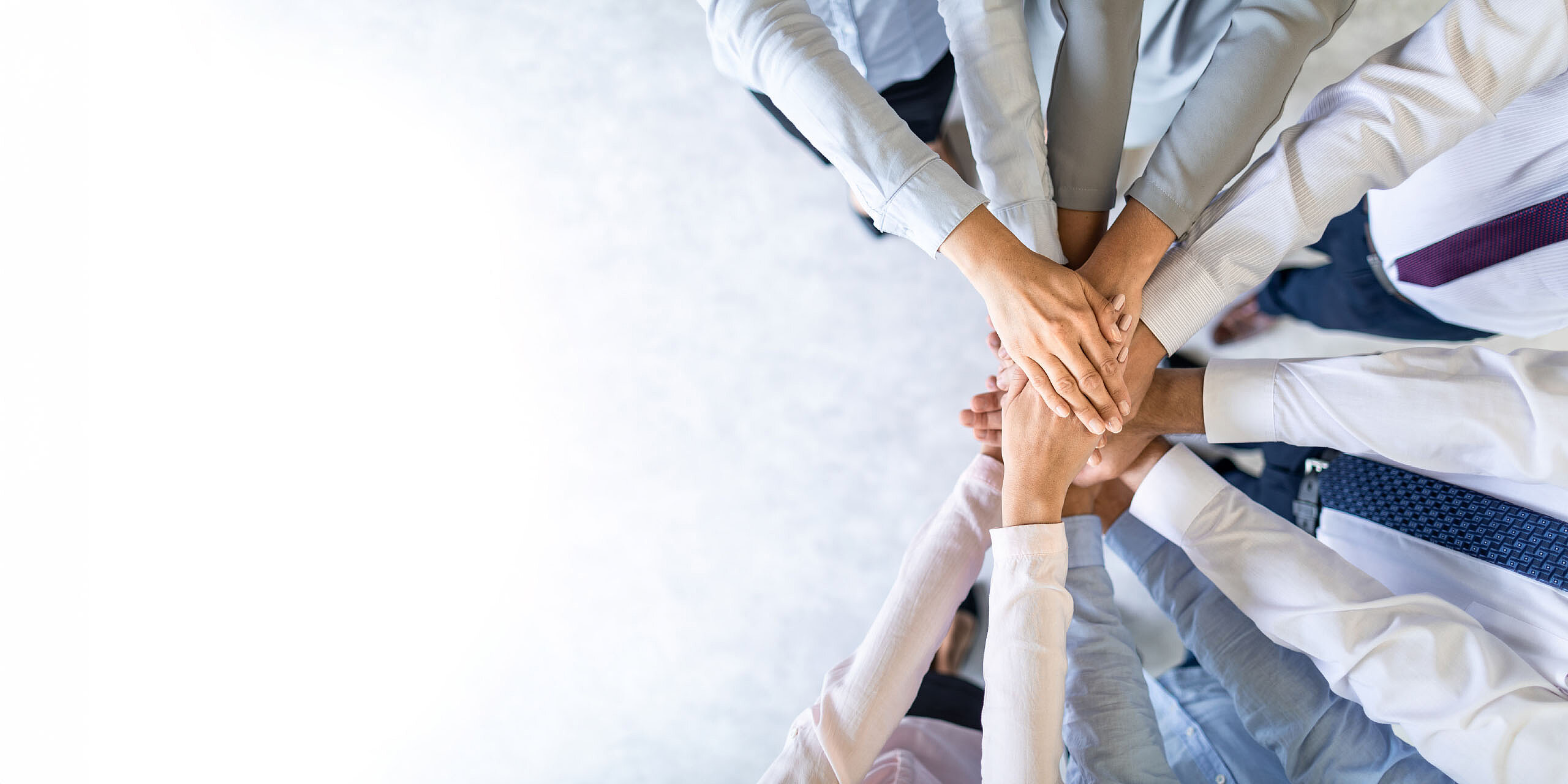 Team legt die Hände übereinander als Zeichen des Zusammenhalts.
