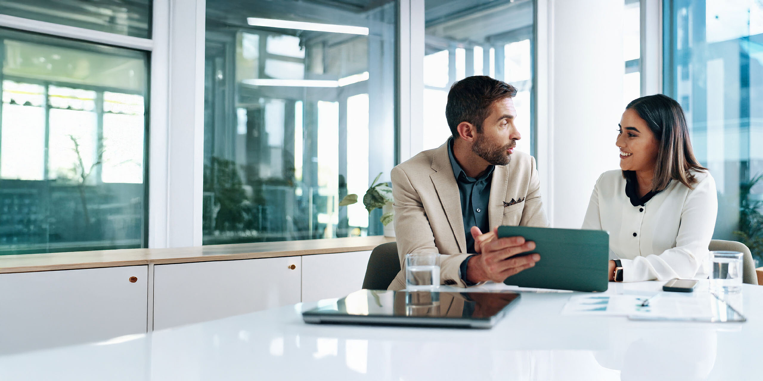 Geschäftsgespräch zwischen einem Mann und einer Frau am Konferenztisch.