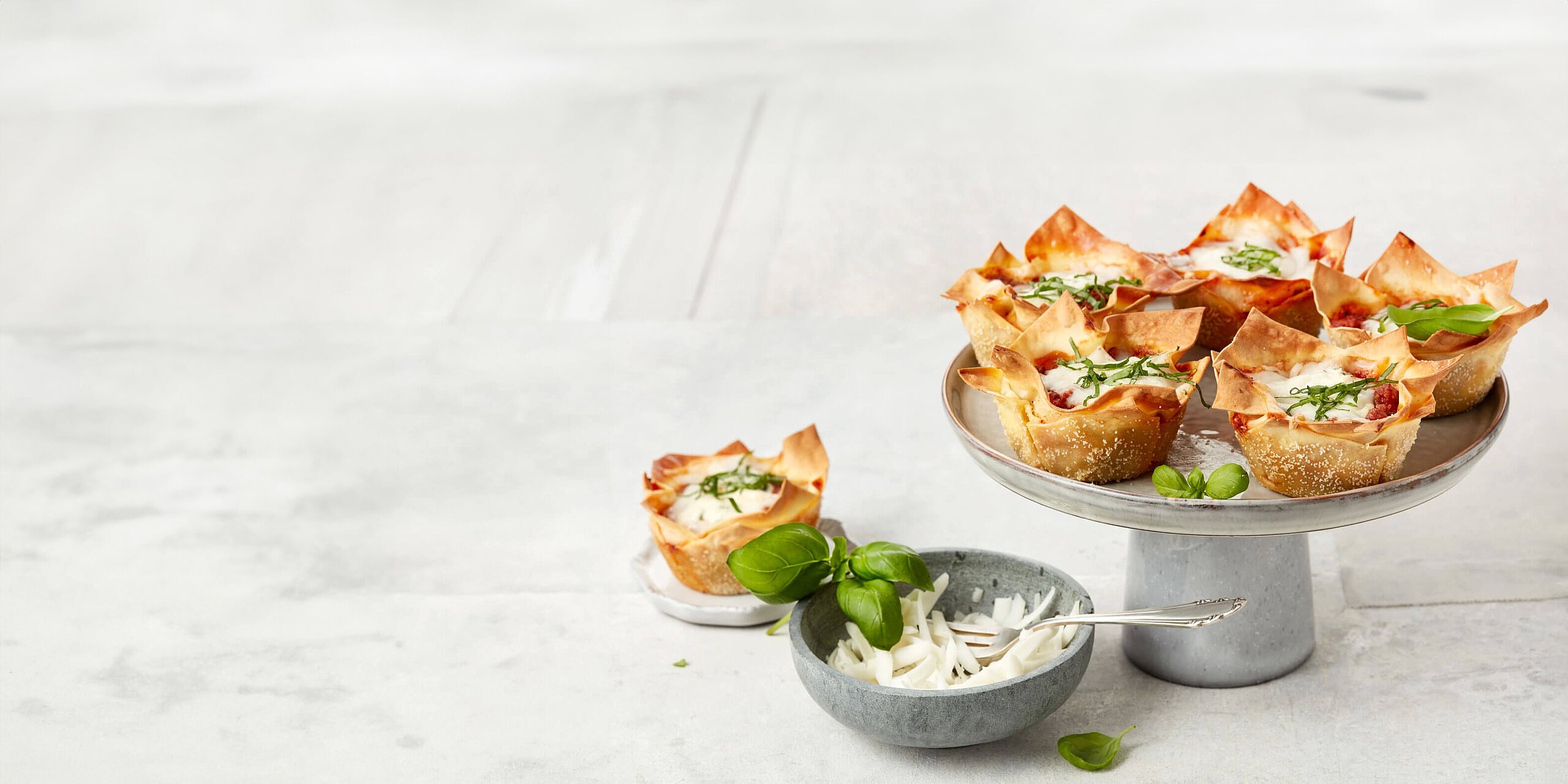 Mehrere Mini-Lasagne auf Teller und Etagere angerichtet
