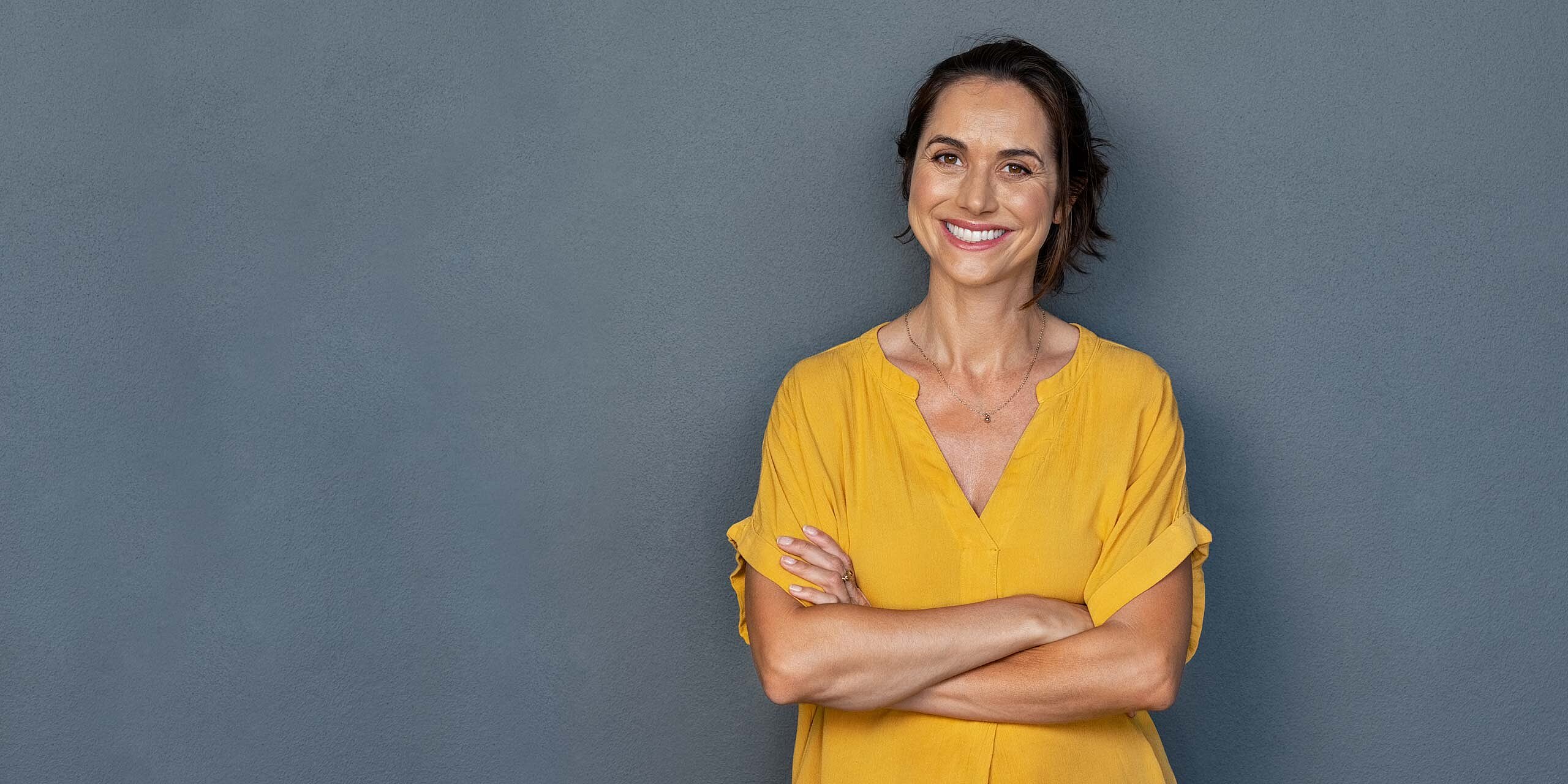 Frau mit roten, lockigen Haaren und gelbem T-Shirt hält eine Gesundheitskarte hoch