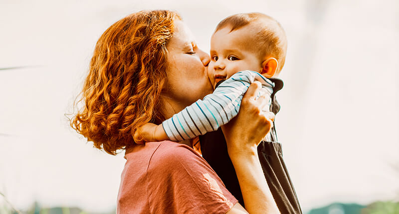 Mutter küsst ihr Baby auf die Backe