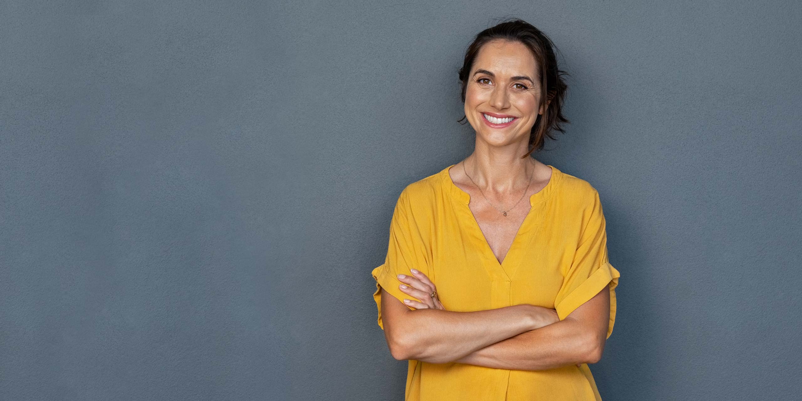 Frau mit roten, lockigen Haaren und gelbem T-Shirt hält eine Gesundheitskarte hoch