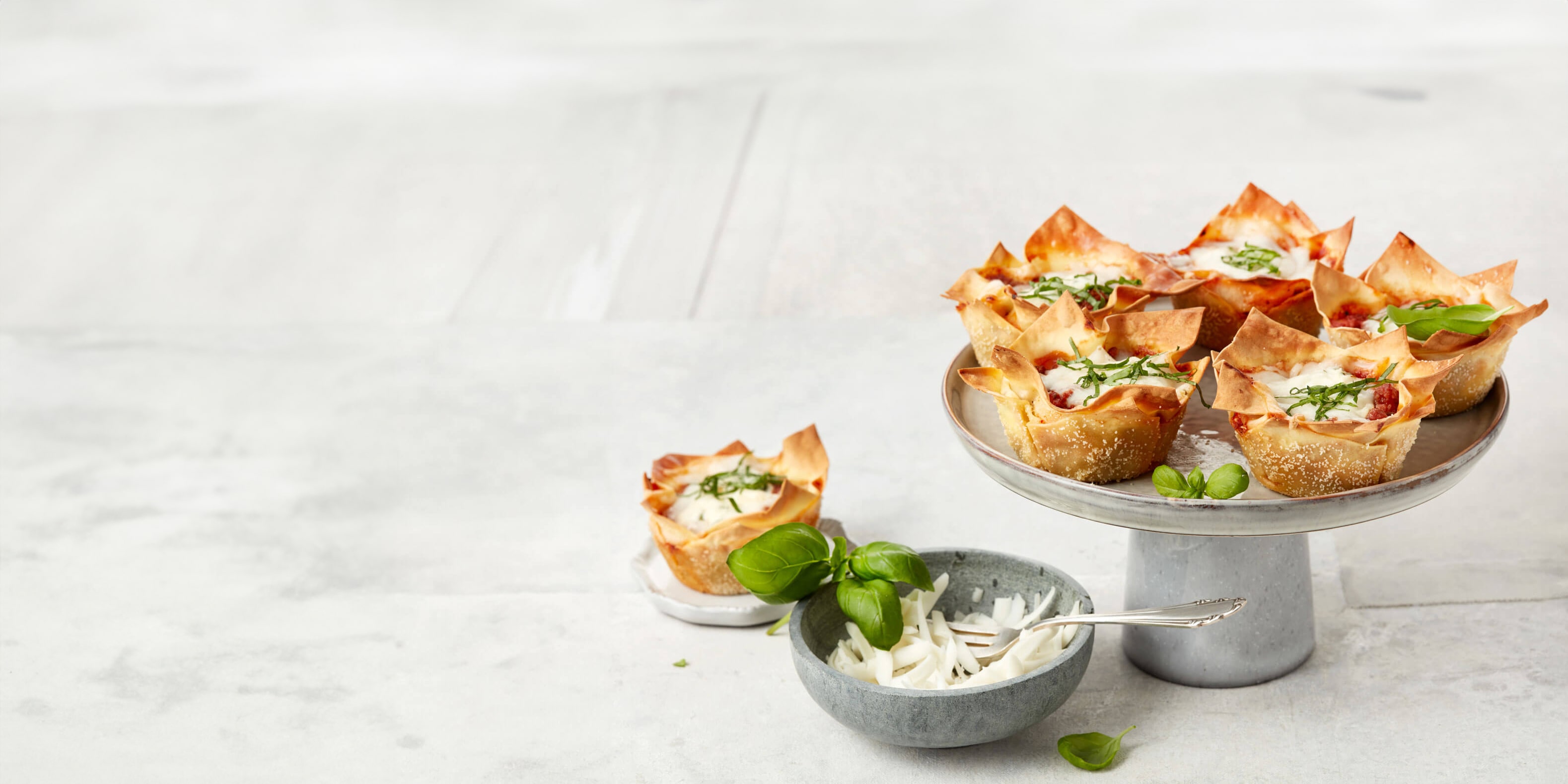 Mehrere Mini-Lasagne auf Teller und Etagere angerichtet