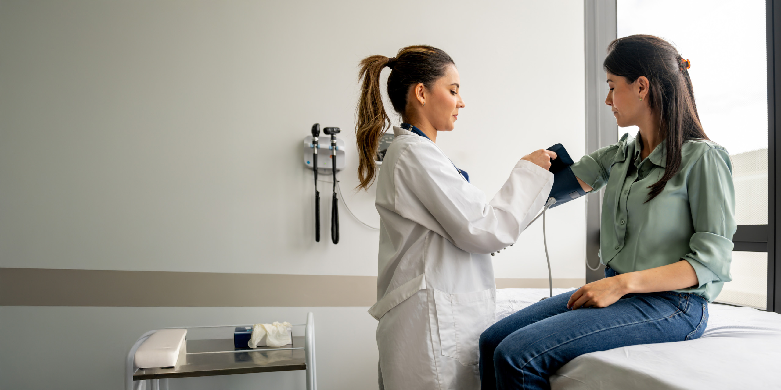 Ärztin misst bei einer Patientin den Blutdruck.